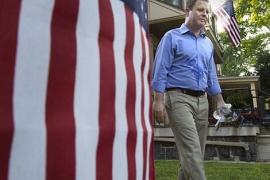 Sean Barney ’98 in a blue shirt and khaki pants walking near an American flag